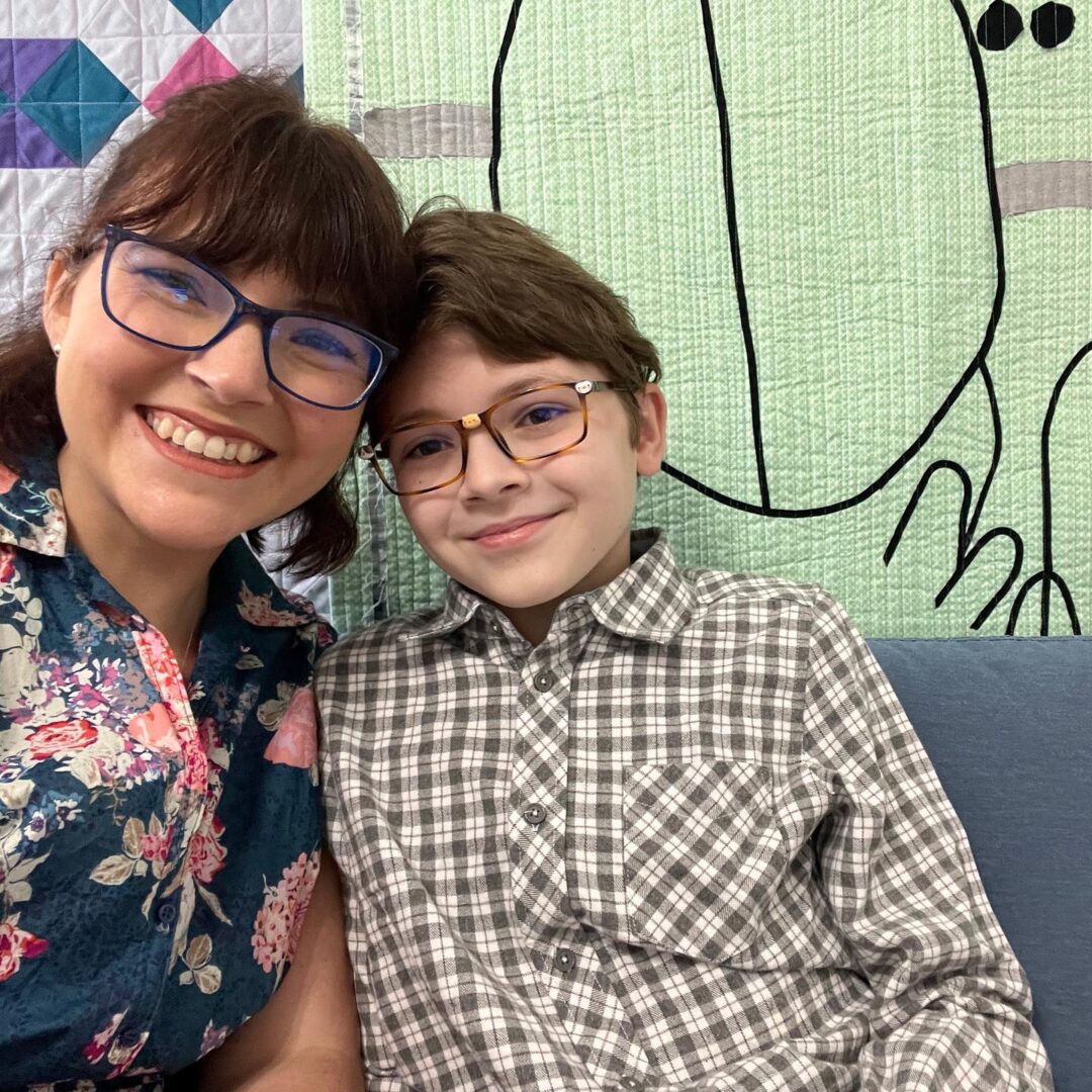 A woman with glasses and a boy posing for a photo.