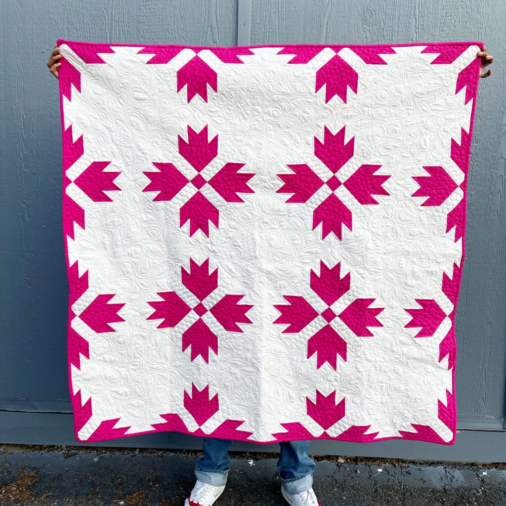 A person holding up a quilt.