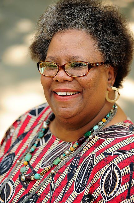 A woman with glasses and a necklace smiles for the camera.