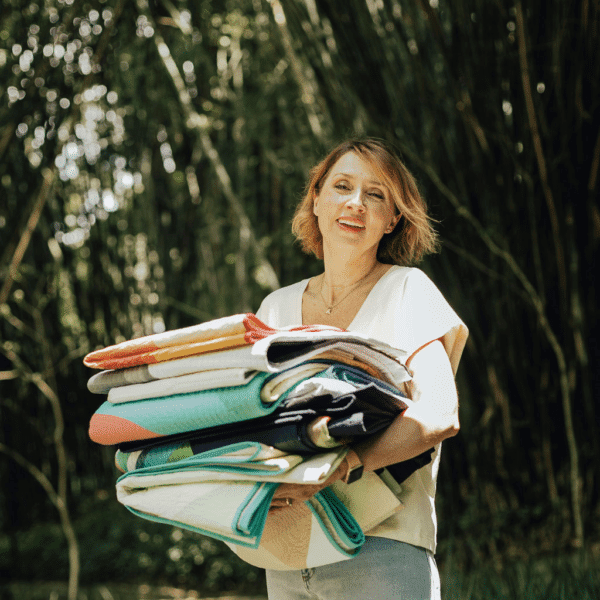 A woman holding a stack of fabric in the woods.