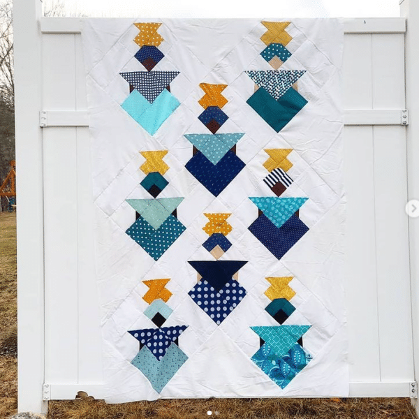 A blue and yellow quilt hanging on a fence.