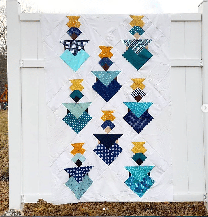 A blue and yellow quilt hanging on a fence.