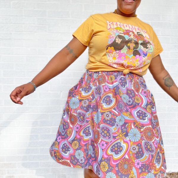 A woman wearing a yellow t - shirt and a paisley skirt.