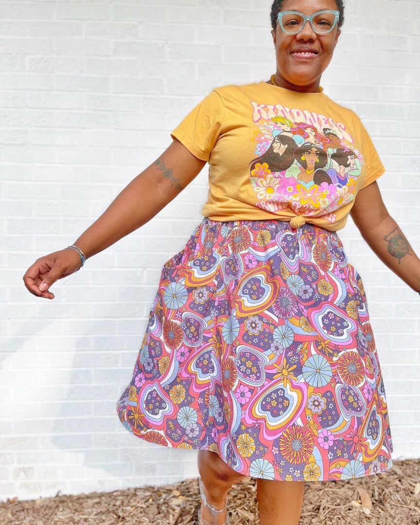 A woman wearing a yellow t - shirt and a paisley skirt.