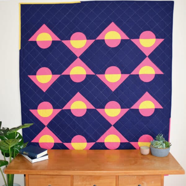 A blue and yellow quilt hanging on a wall.