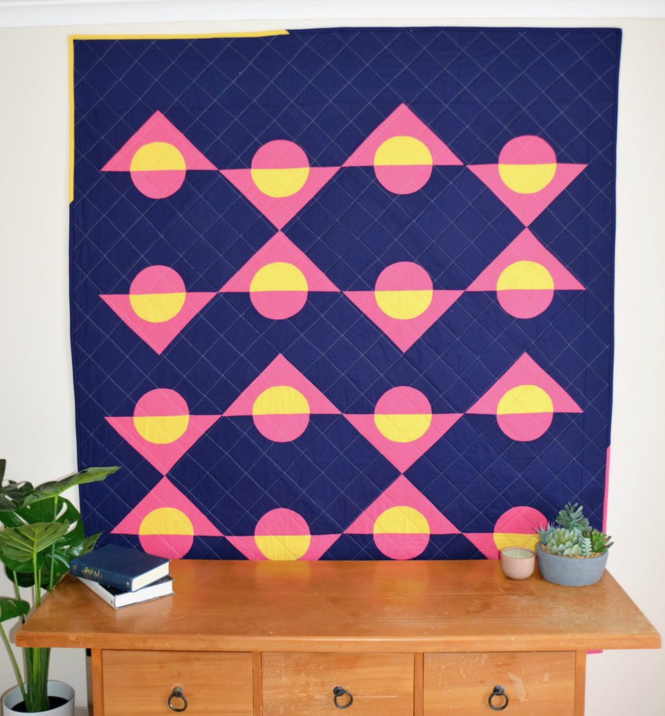 A blue and yellow quilt hanging on a wall.