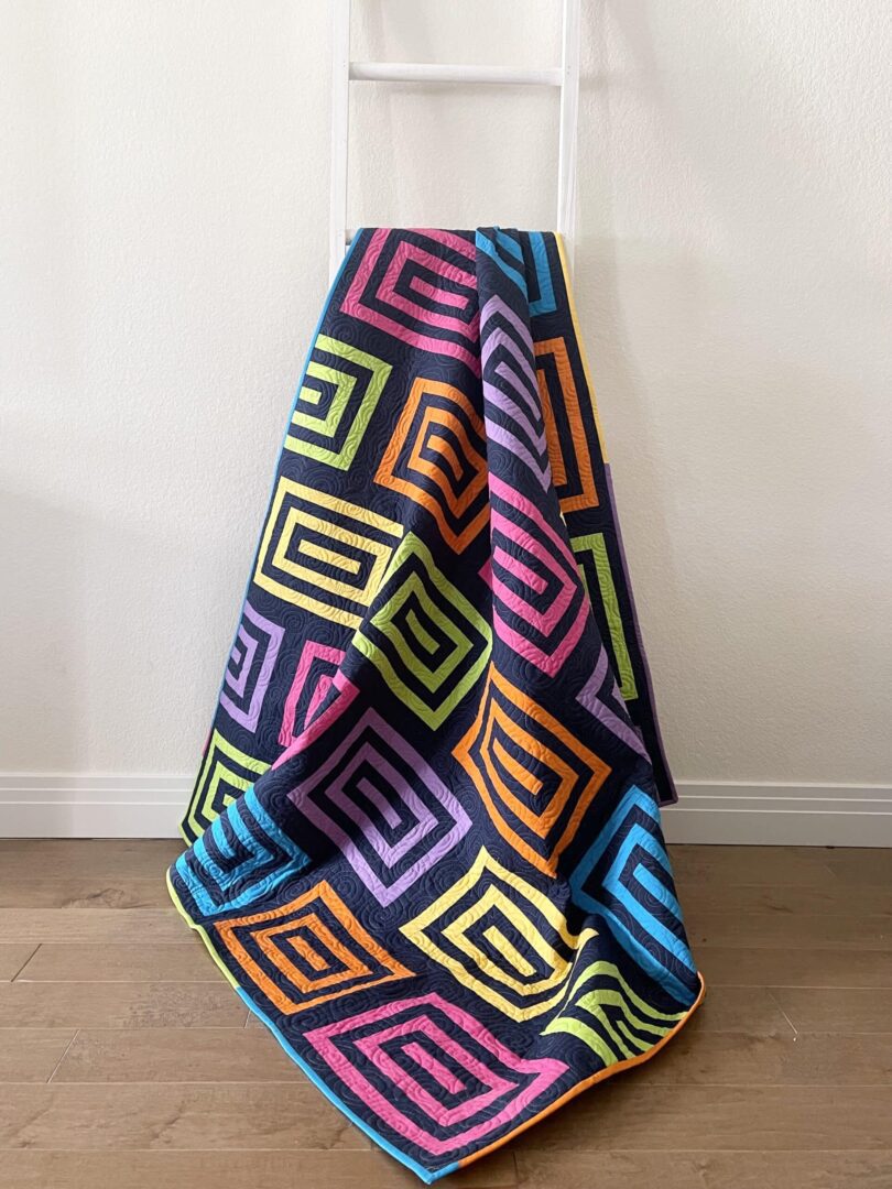 A colorful blanket sitting on the floor next to a wall.