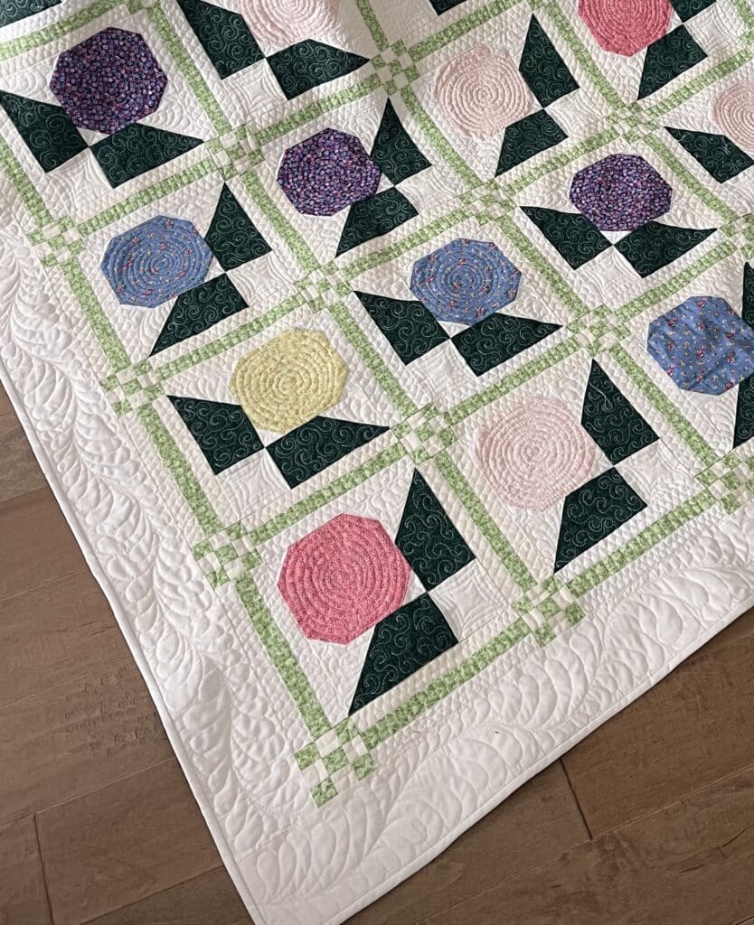 A quilt with colorful flowers on a wooden floor.