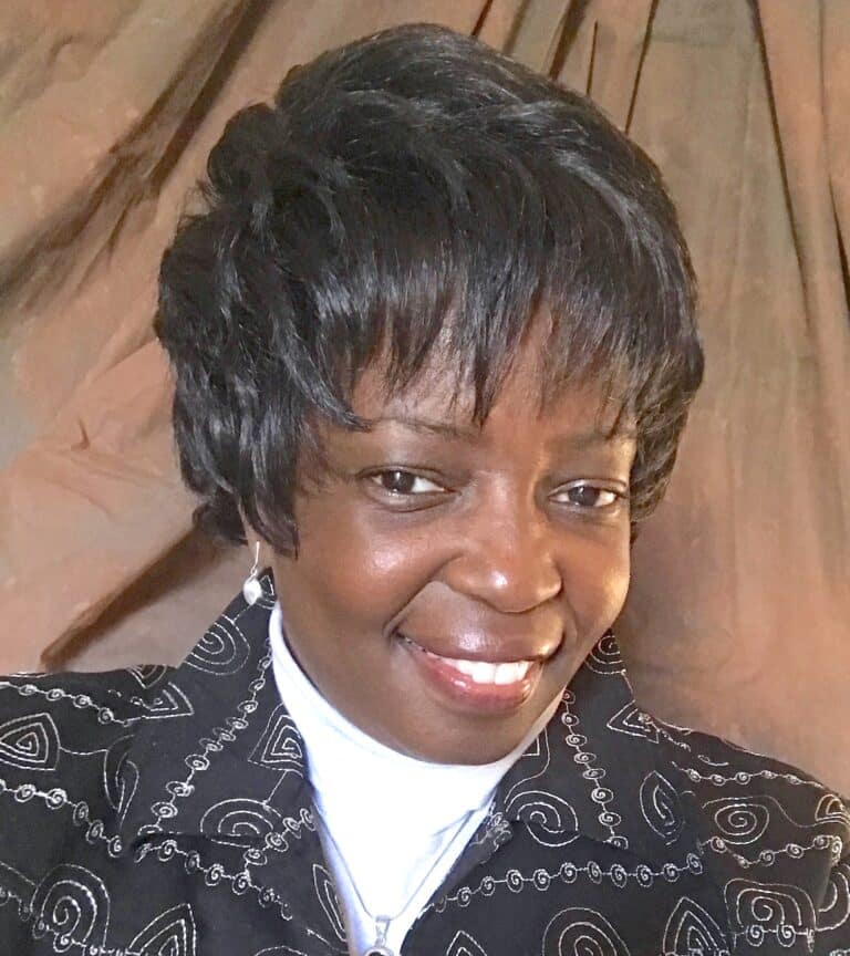 A woman in a black jacket smiles for the camera.