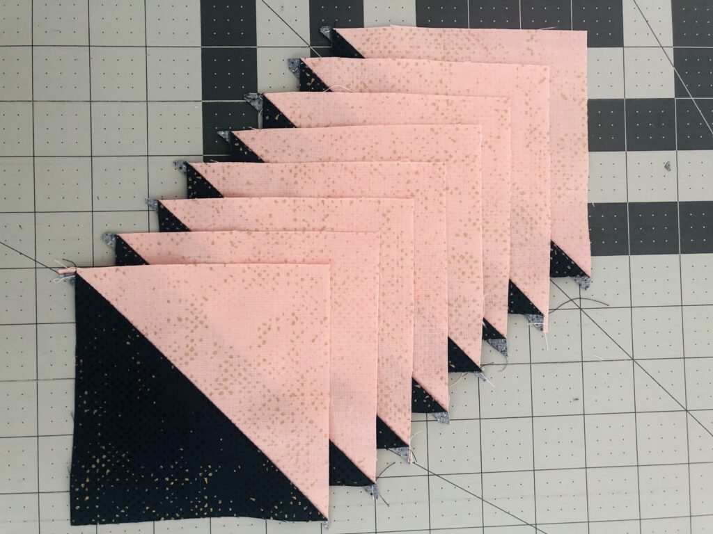 Pink and black quilt blocks on a cutting board.