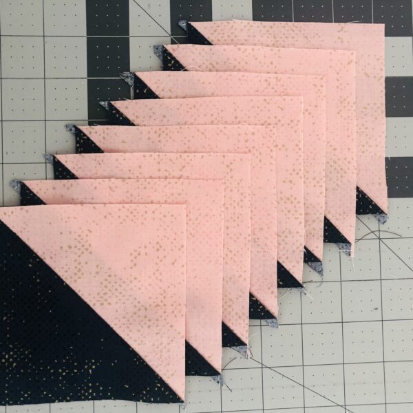 Pink and black quilt blocks on a cutting board.