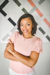 A woman in pink shirt with arms crossed.