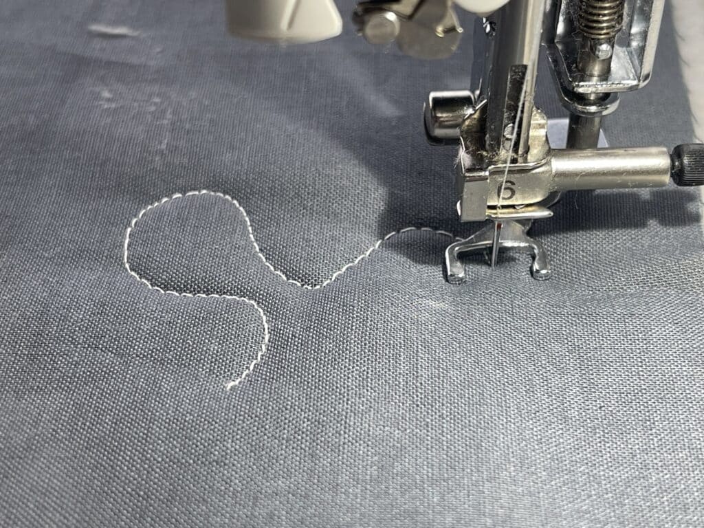 A sewing machine is being used to sew a piece of fabric.