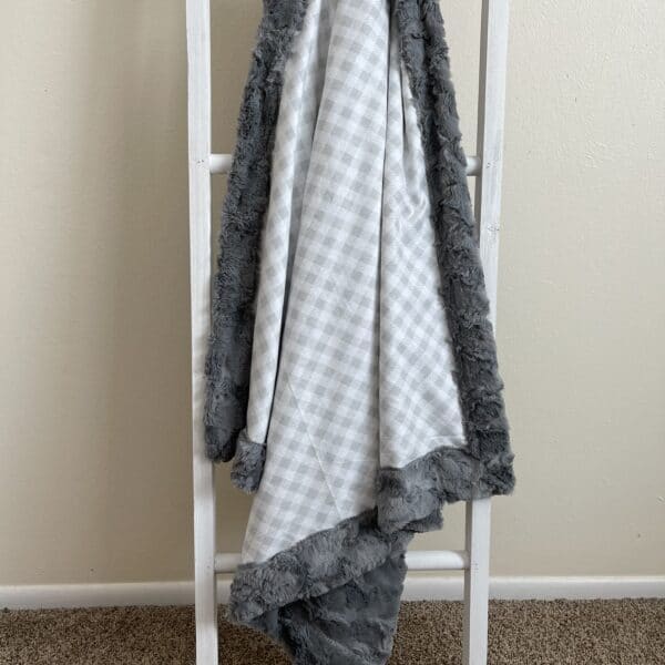 A ladder with a grey and white blanket on it.