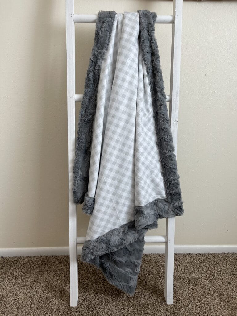 A ladder with a grey and white blanket on it.