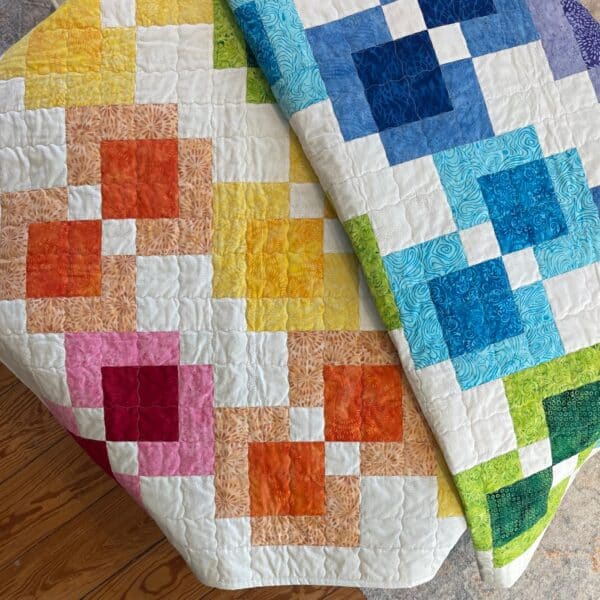 A colorful quilt is folded on the floor.