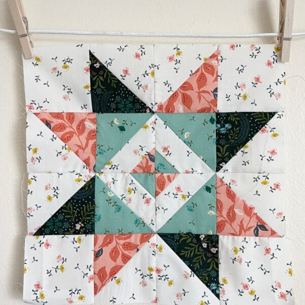 A quilt block hanging on a clothes line.