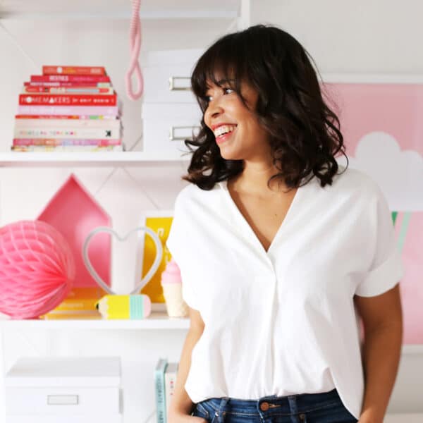 A woman in jeans and a white shirt standing in front of a shelf.