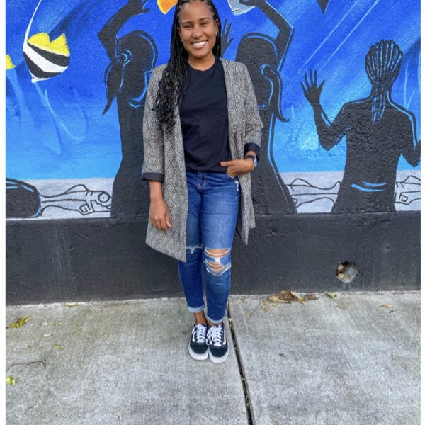 A young woman standing in front of a mural.