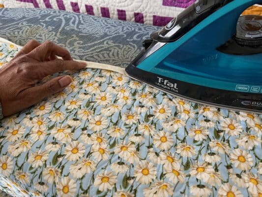 A person using an iron to work on a quilt.
