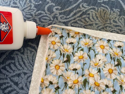 A person is using glue to fix the edge of a quilt.