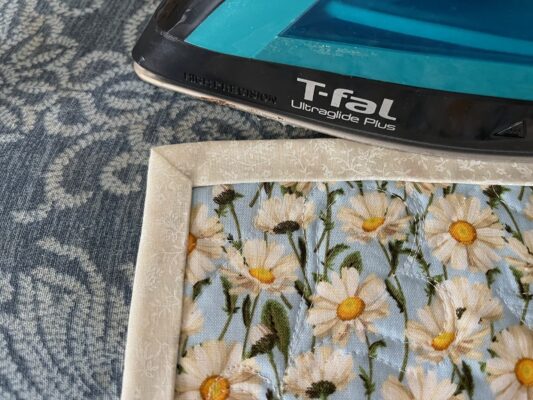 A tablet is sitting on the table next to a flower print.