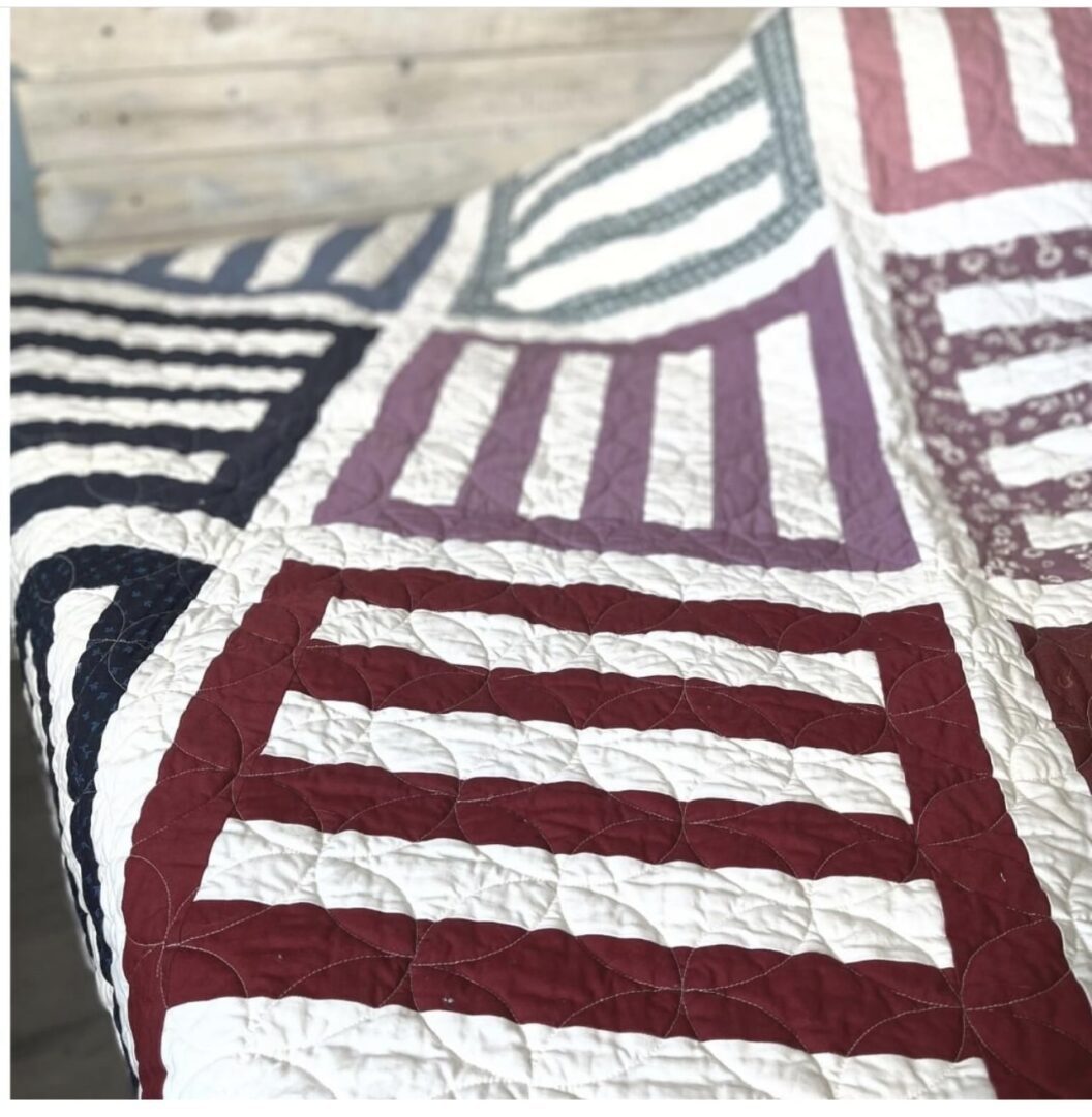 A close up of a quilt with red, white and blue stripes.