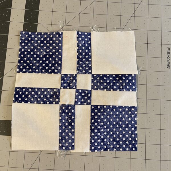 A blue and white quilt block on a cutting mat.
