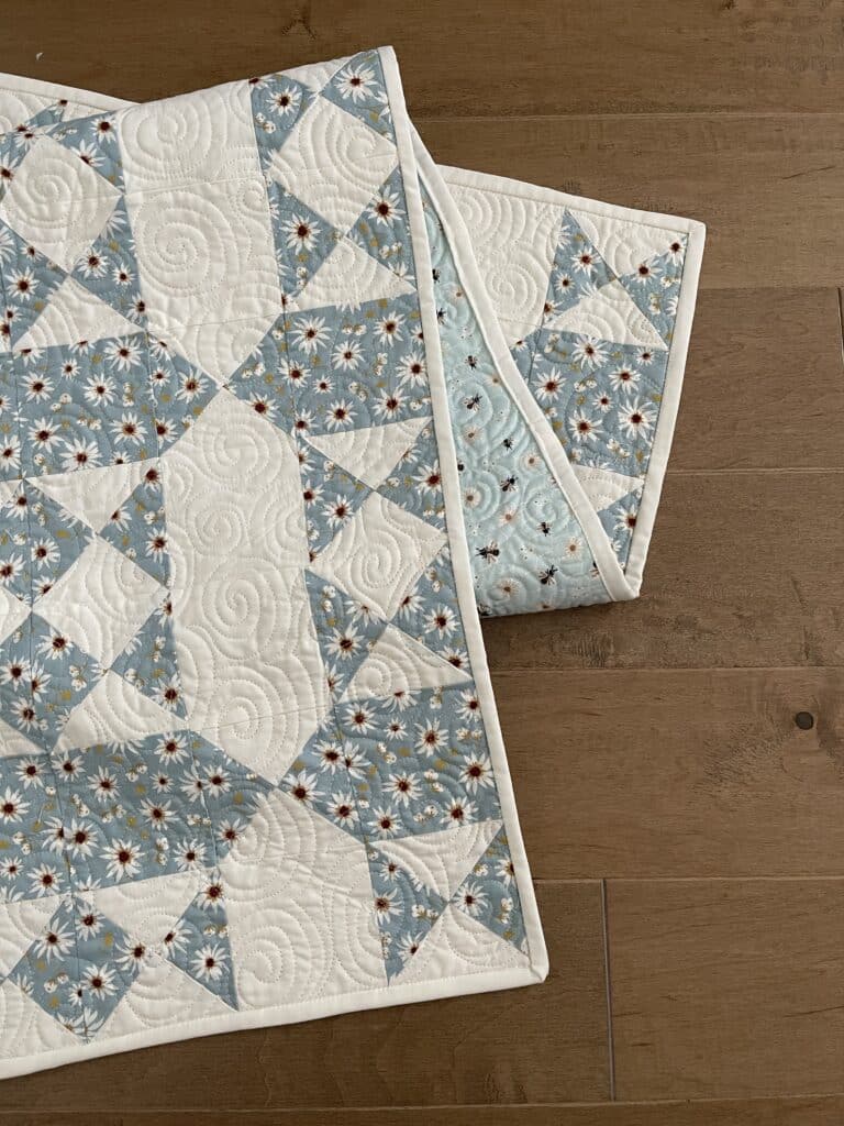 A blue and white quilted table runner on a wooden floor.