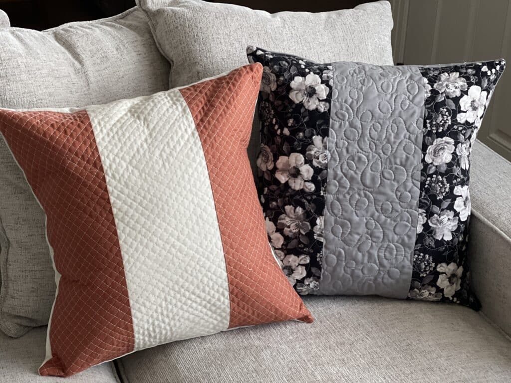 Two quilted pillows on a couch.