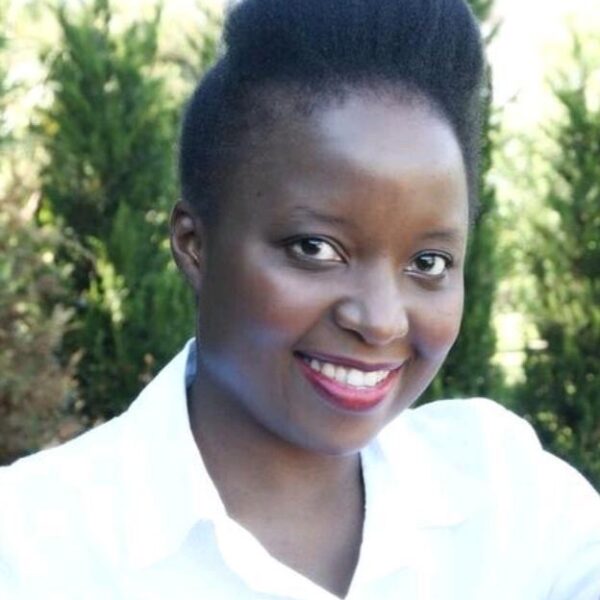 A woman in a white shirt is smiling while holding a cup.