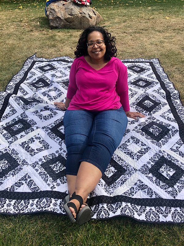 A woman laying on a black and white quilt.