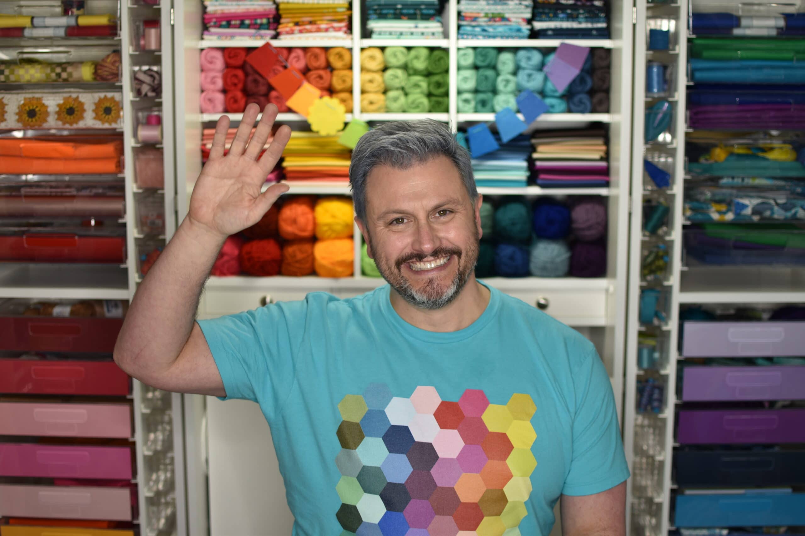 A man is standing in front of a room full of yarn.