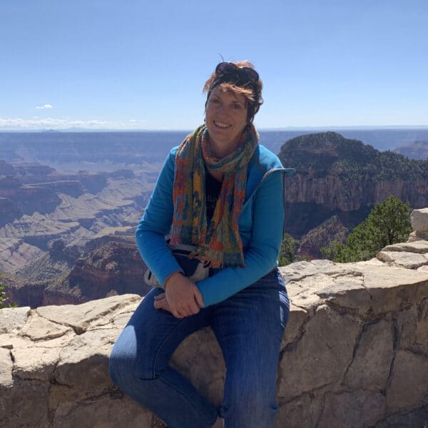 A woman sitting on a ledge overlooking the grand canyon.