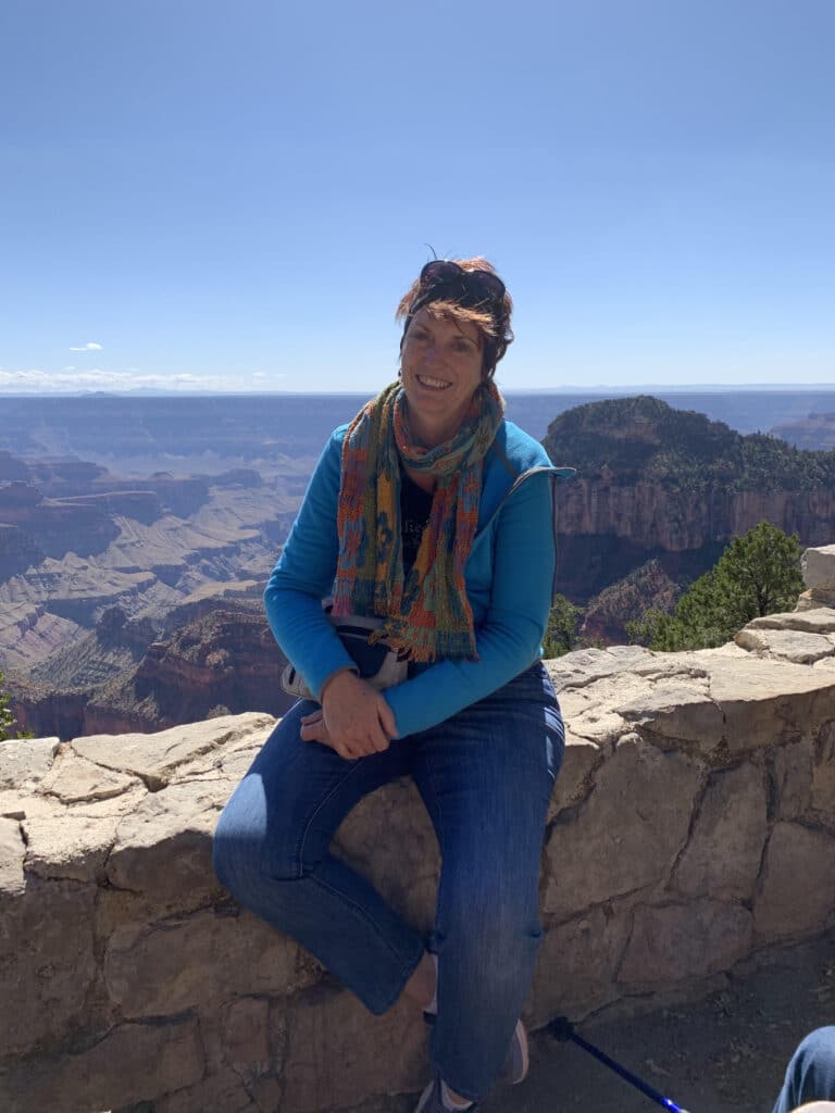 A woman sitting on a ledge overlooking the grand canyon.