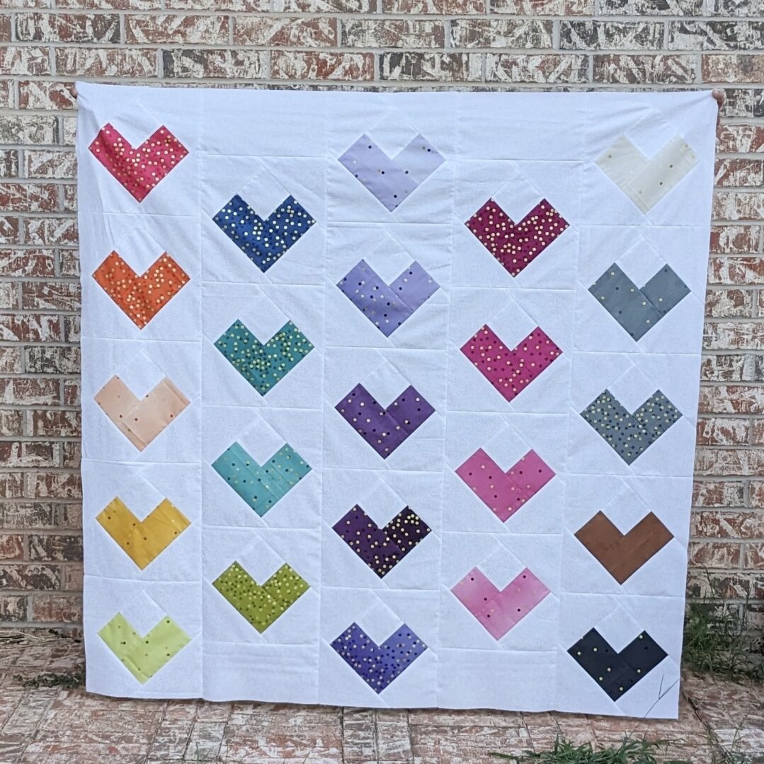A quilt with hearts on it sitting outside.