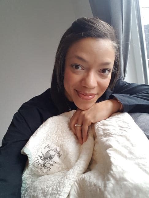 A woman laying on a couch with a blanket.