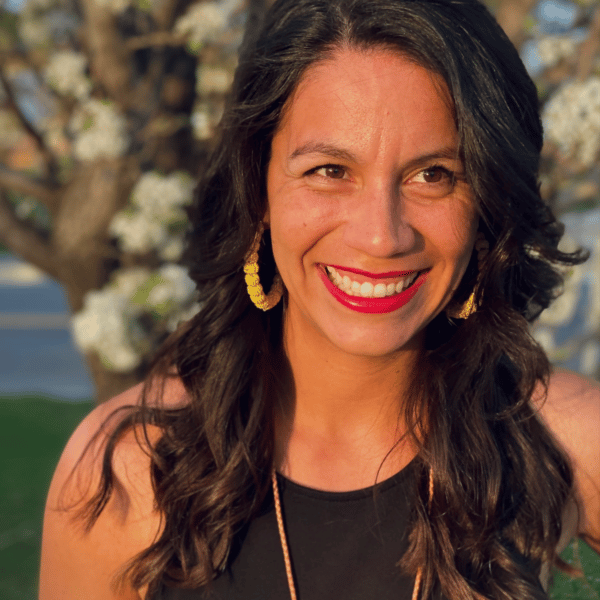 A smiling woman in a black top and colorful necklace.