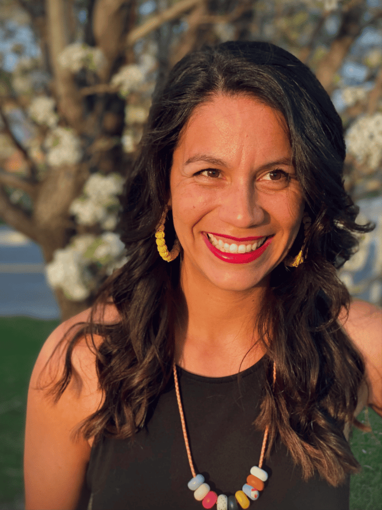 A smiling woman in a black top and colorful necklace.