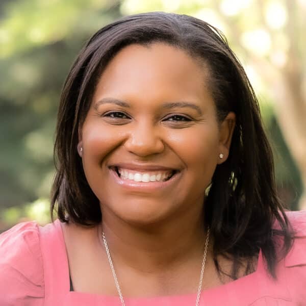 A smiling black woman in a pink top.