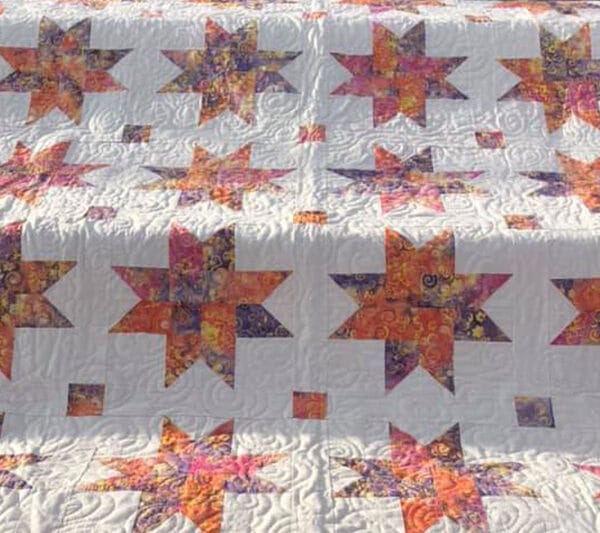 A quilt with orange and white stars on it.